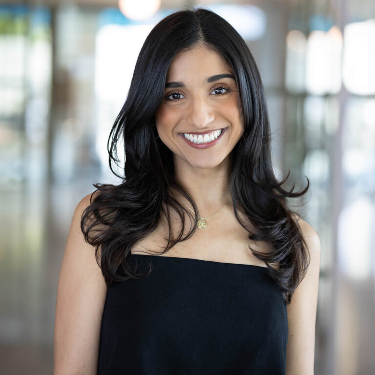 Smiling woman in black dress indoors with blurred background