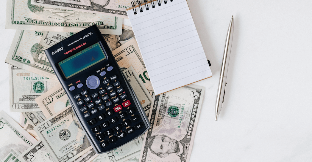 An image of a calculator resting on a pile of money symbolizing the Payroll Tax Deferrals.