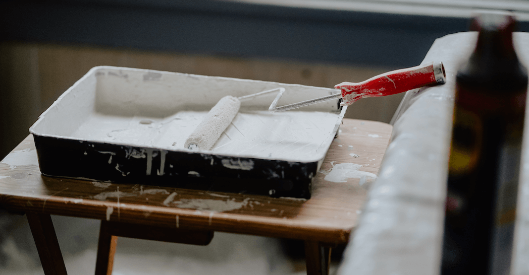 An image of a painter rolling primer onto their paint brush.
