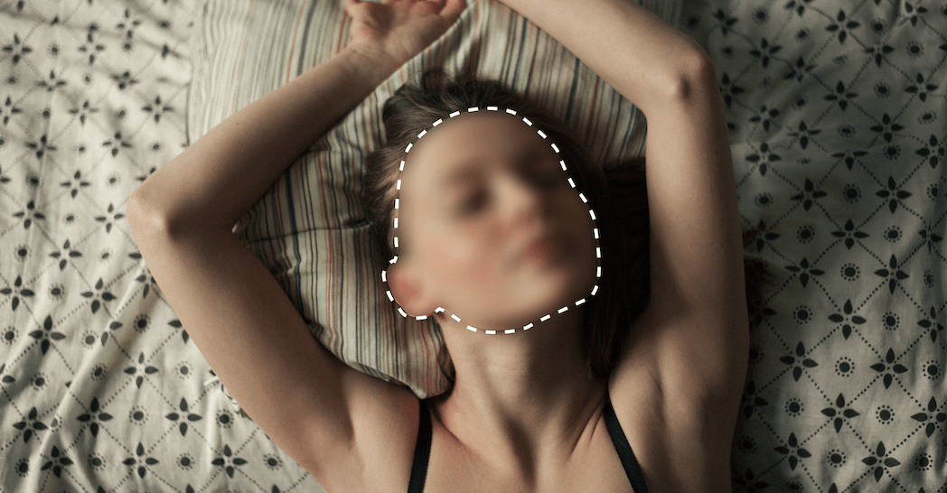 An image of a woman lying on bed with her face blurred.