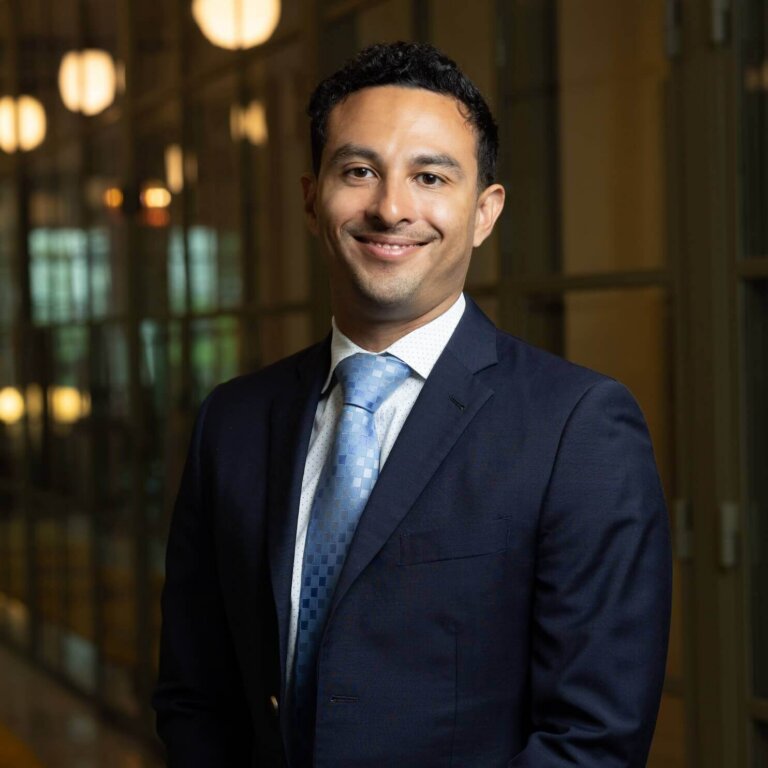 Smiling man in suit standing in modern office hallway