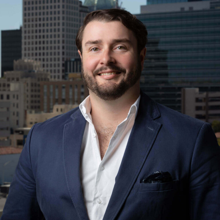 Businessman in blue blazer smiling with urban skyline backdrop