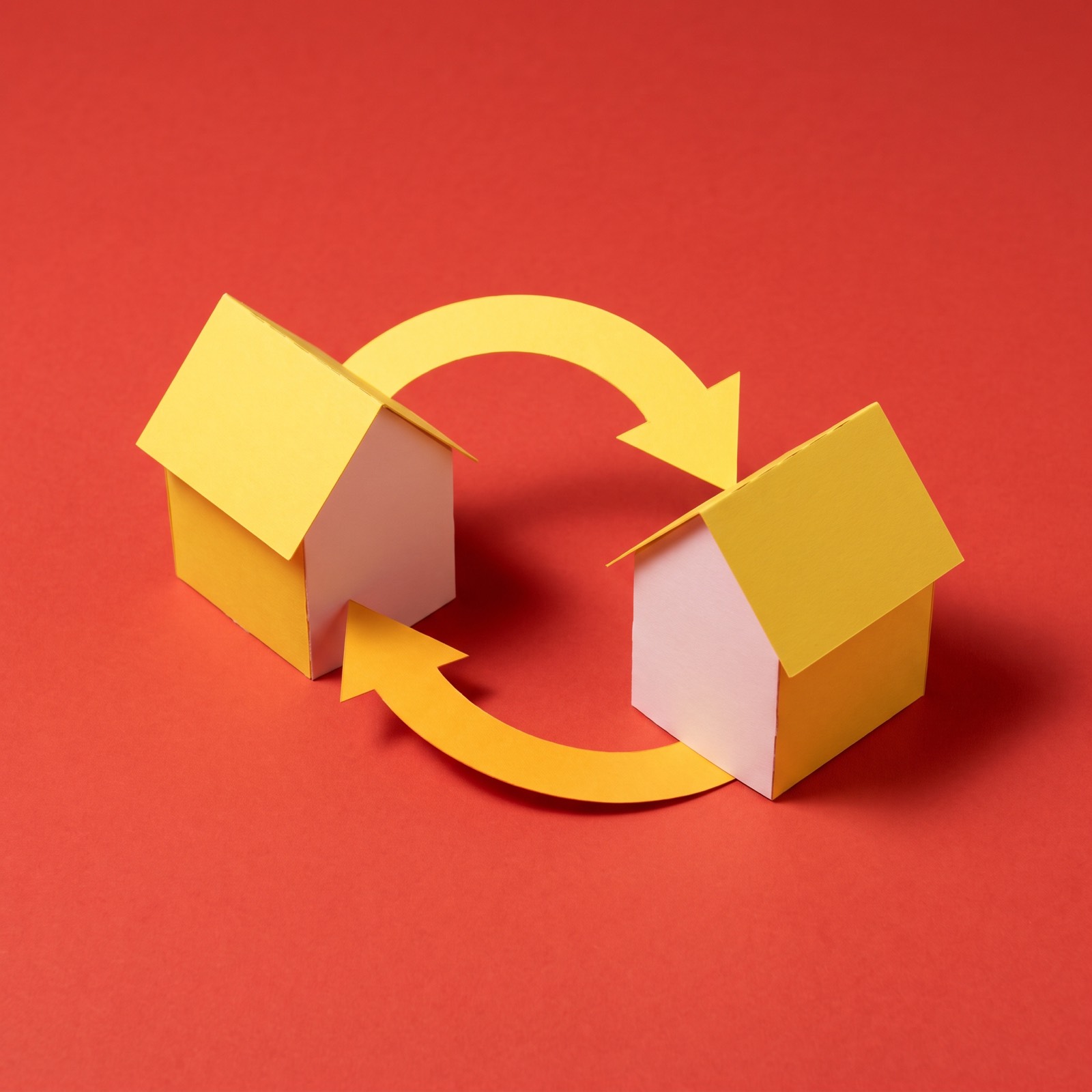 Paper sculpture of two small houses facing each other, with a looping arrow between them