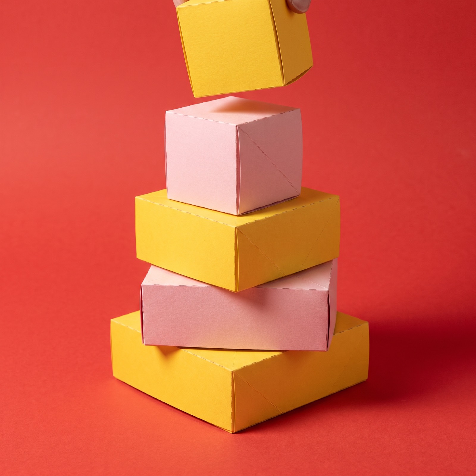 Paper sculpture of a stack of building blocks with one more block being added on top