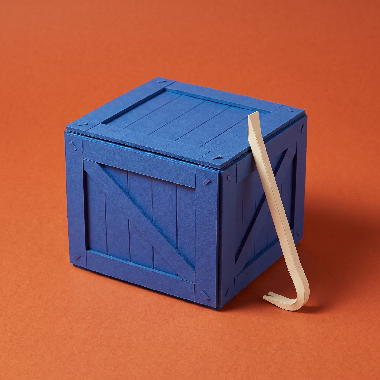 A nailed-shut crate with a crowbar leaning on it