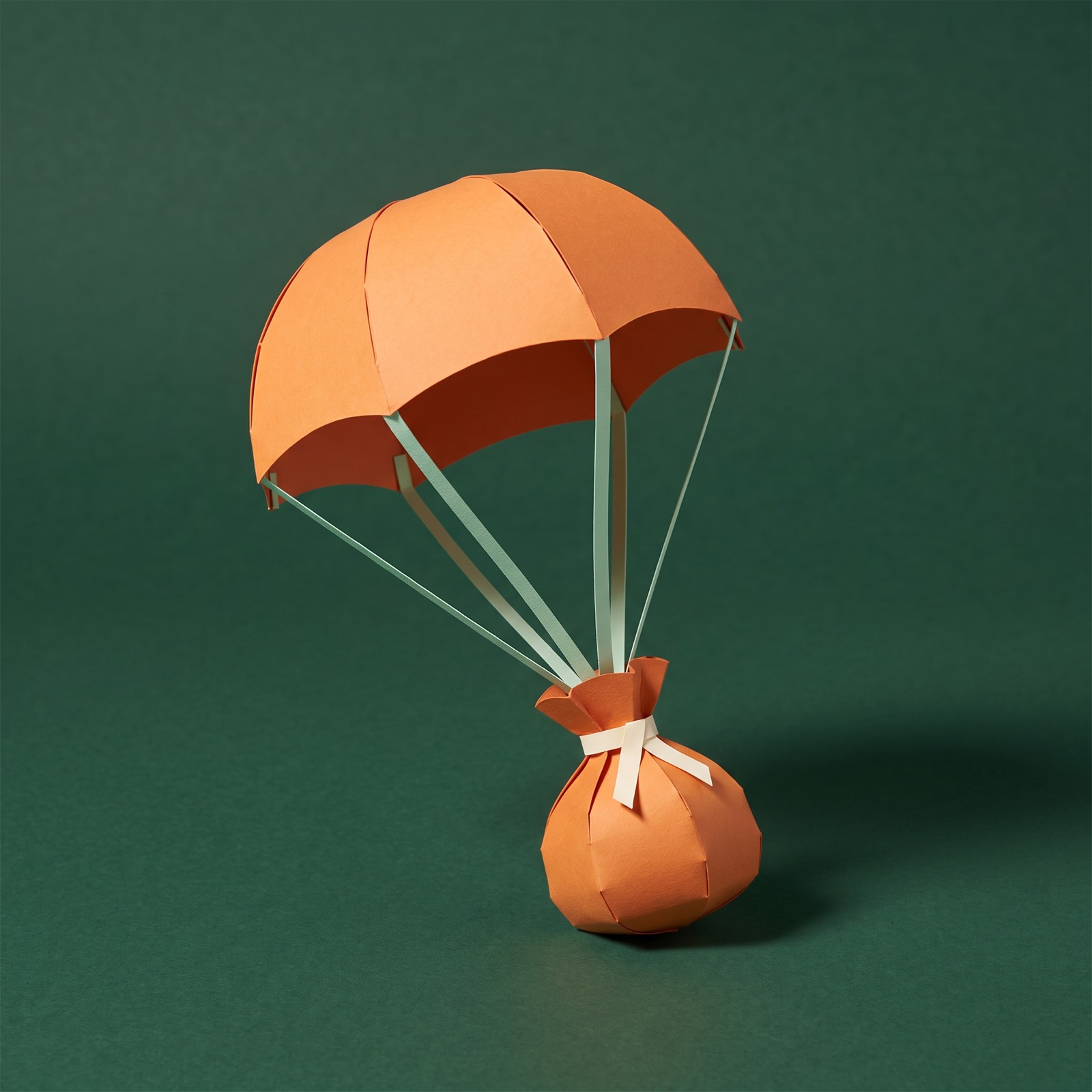 Paper sculpture of a parachute carrying a small bag of money