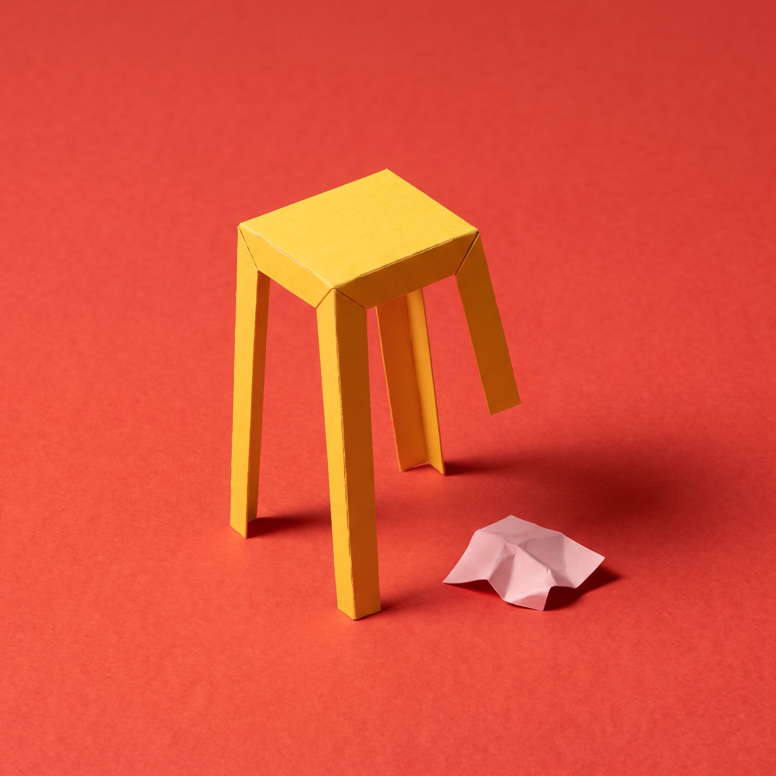 Paper sculpture of a three-legged stool with one leg missing