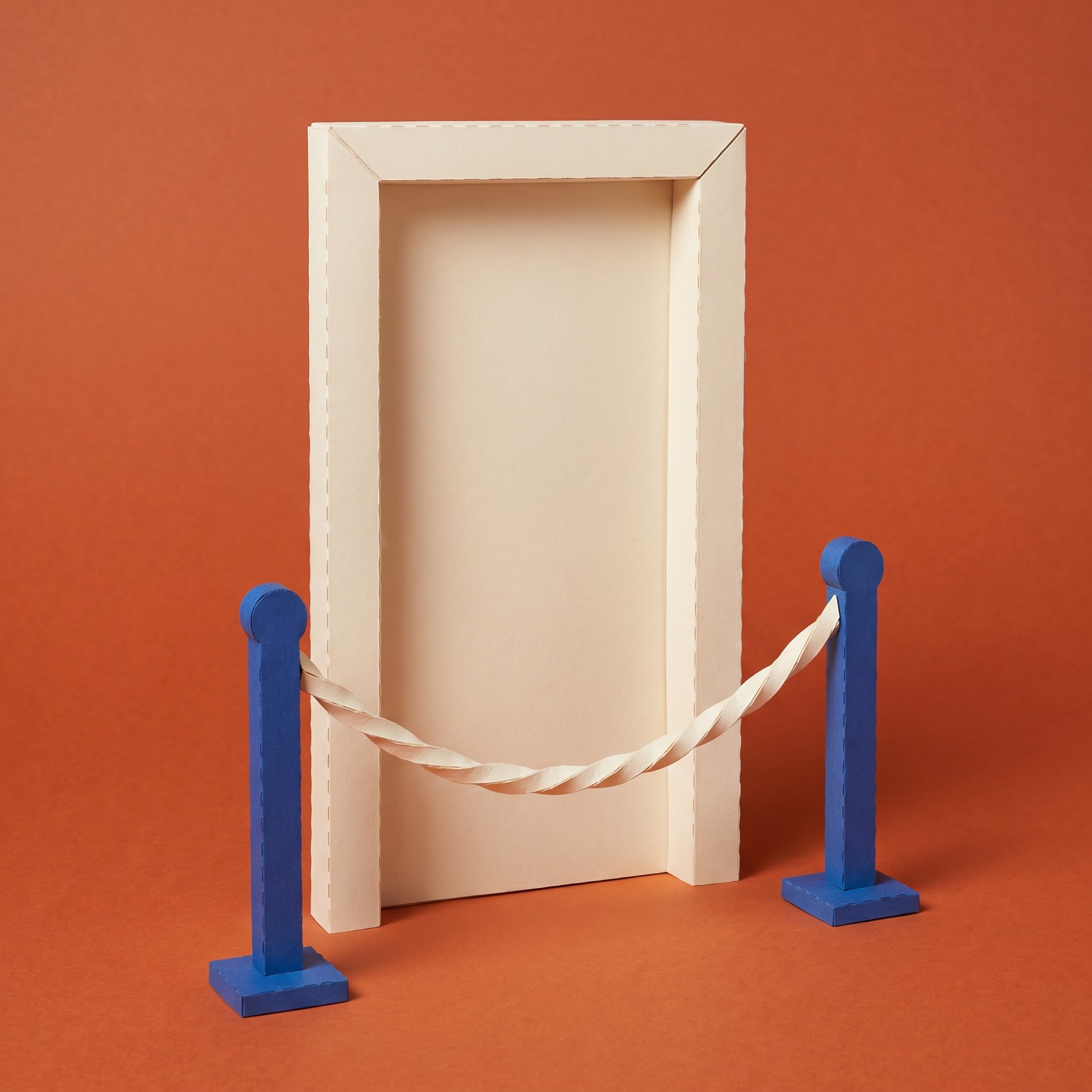Paper sculpture of a tall door with a rope barrier strung between two posts in front of it