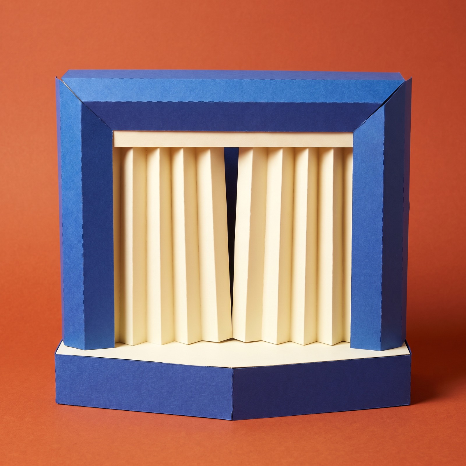 Paper sculpture of a small toy theatre with its curtains drawn closed