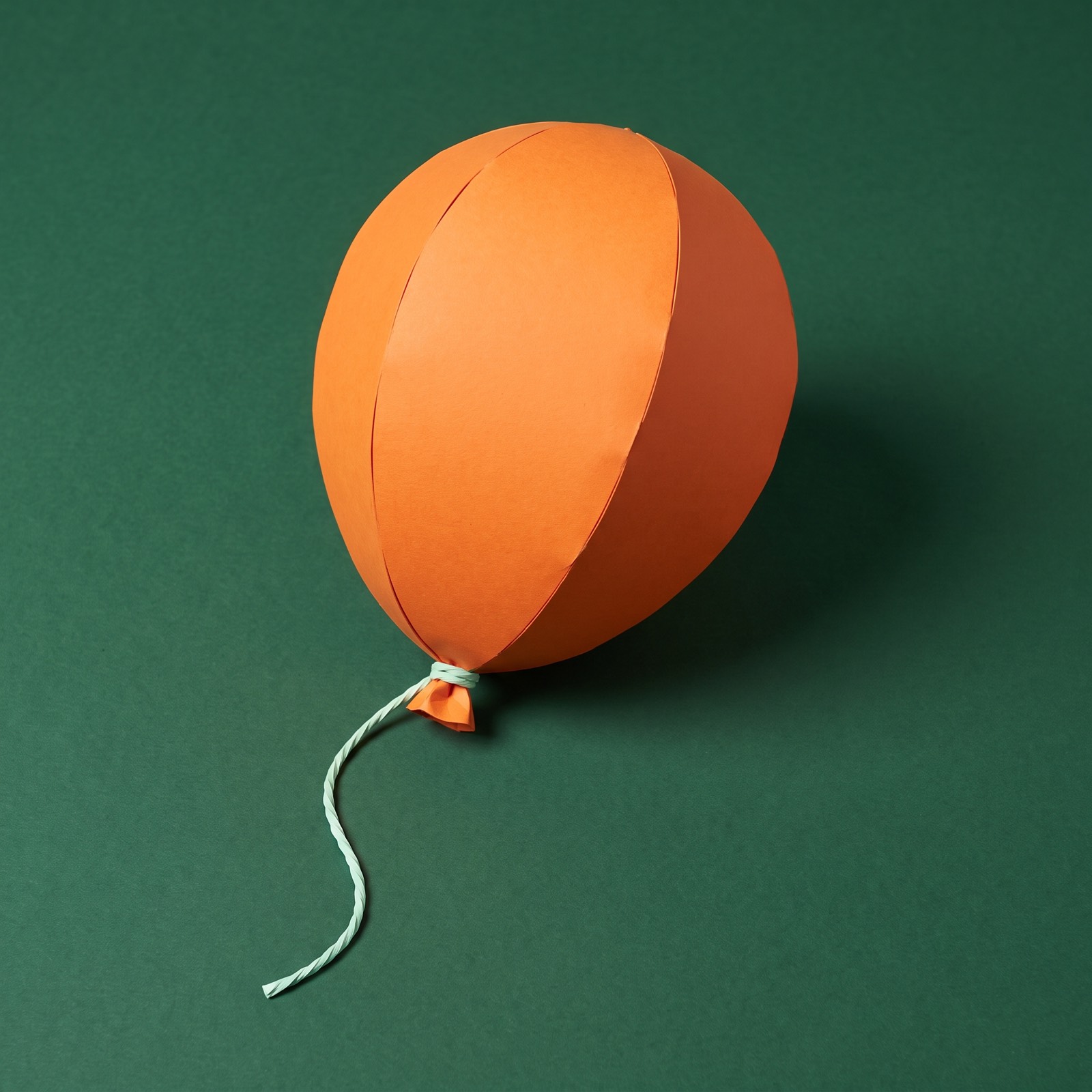 Paper sculpture of a single balloon, very full, on a string