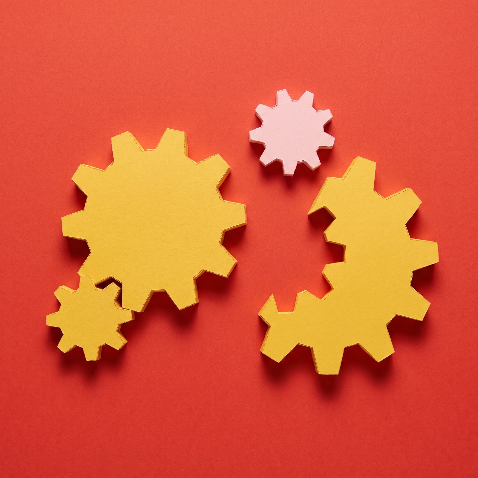 Paper sculpture of a set of interlocking gears with one gear missing from the middle