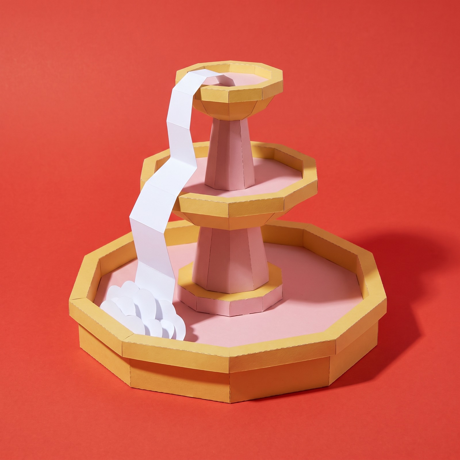 Paper sculpture of a tiered fountain with water spilling from one basin down to the next