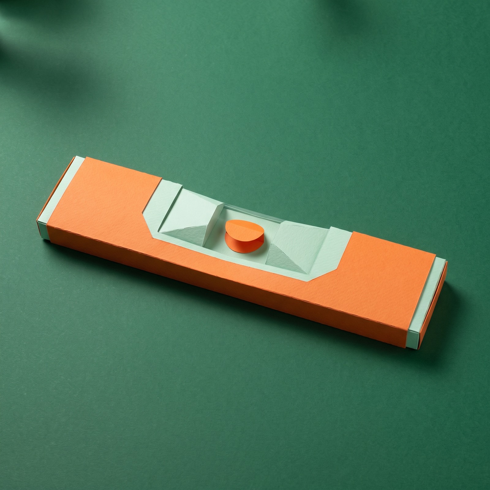 Paper sculpture of a carpenter's spirit level lying flat, its bubble resting just off centre